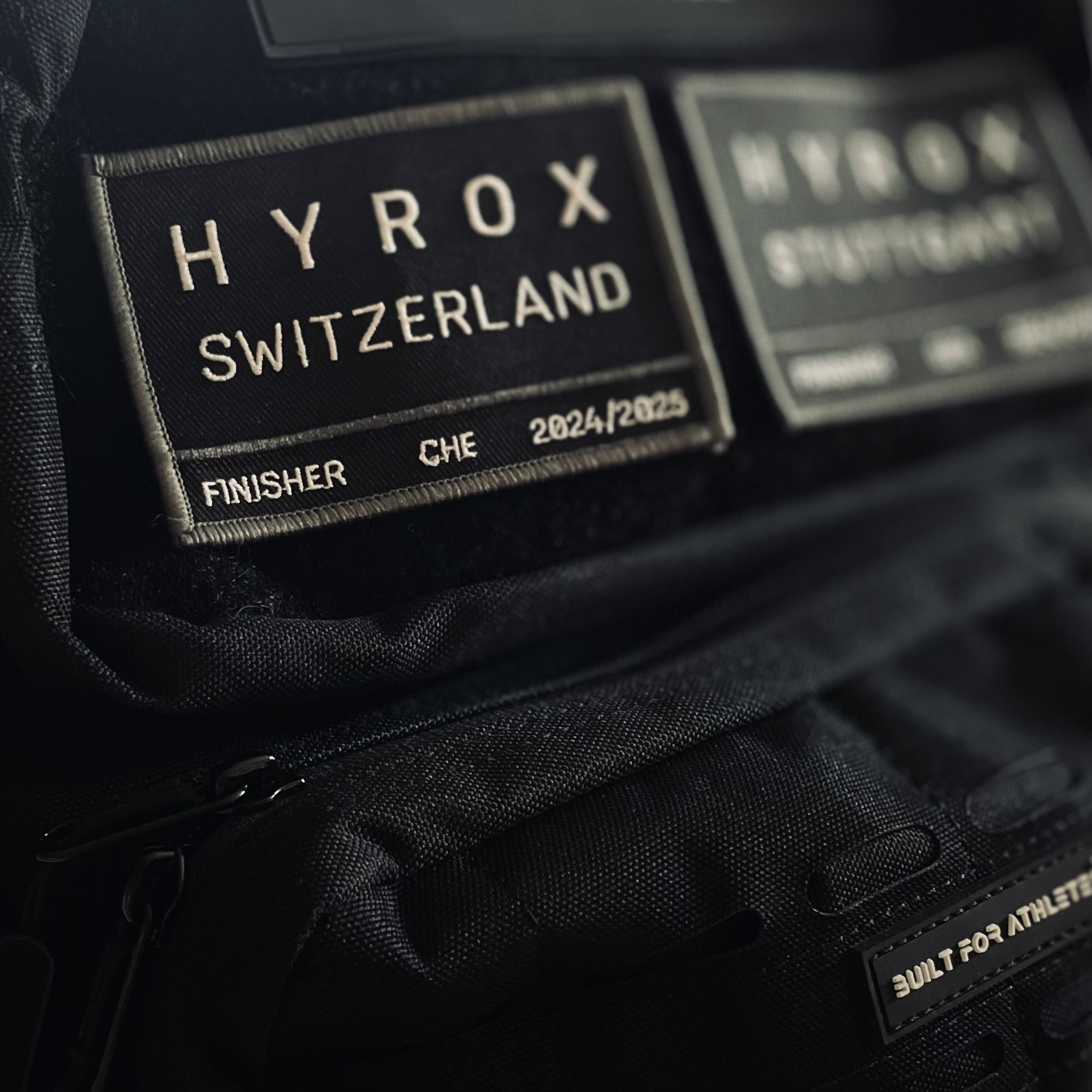 Hyrox-Badges an schwarzem Rucksack - im Vordergrund Hyrox Switzerland. 