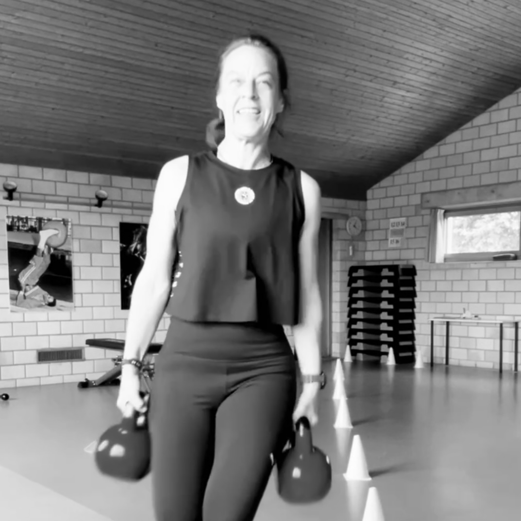 Das Bild zeigt Jo Angele mit einer Kettlebell in jeder Hand. 