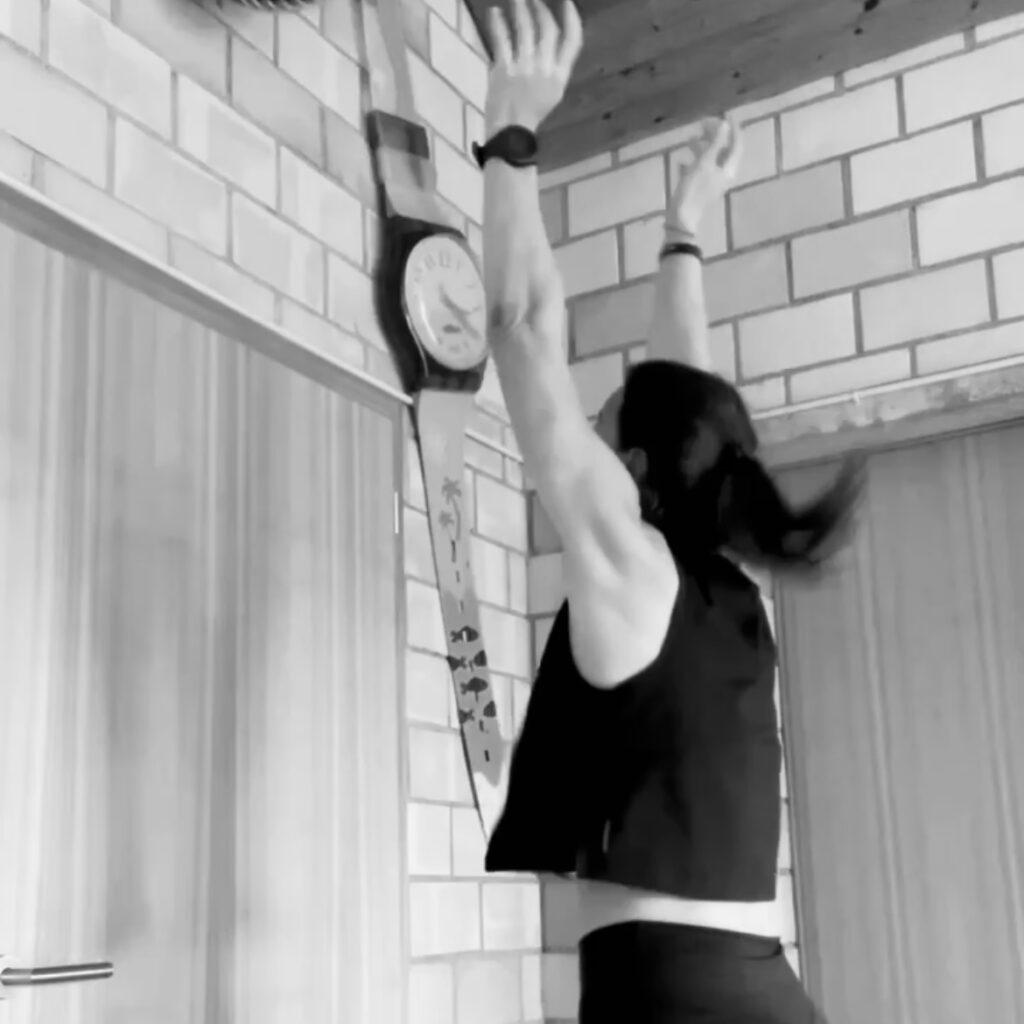 Das Bild zeigt Jo Angele bei der Übung "Wall Balls", die Hände sind über den Kopf gestreckt und haben sobeben einen Ball in die Luft geworfen. 