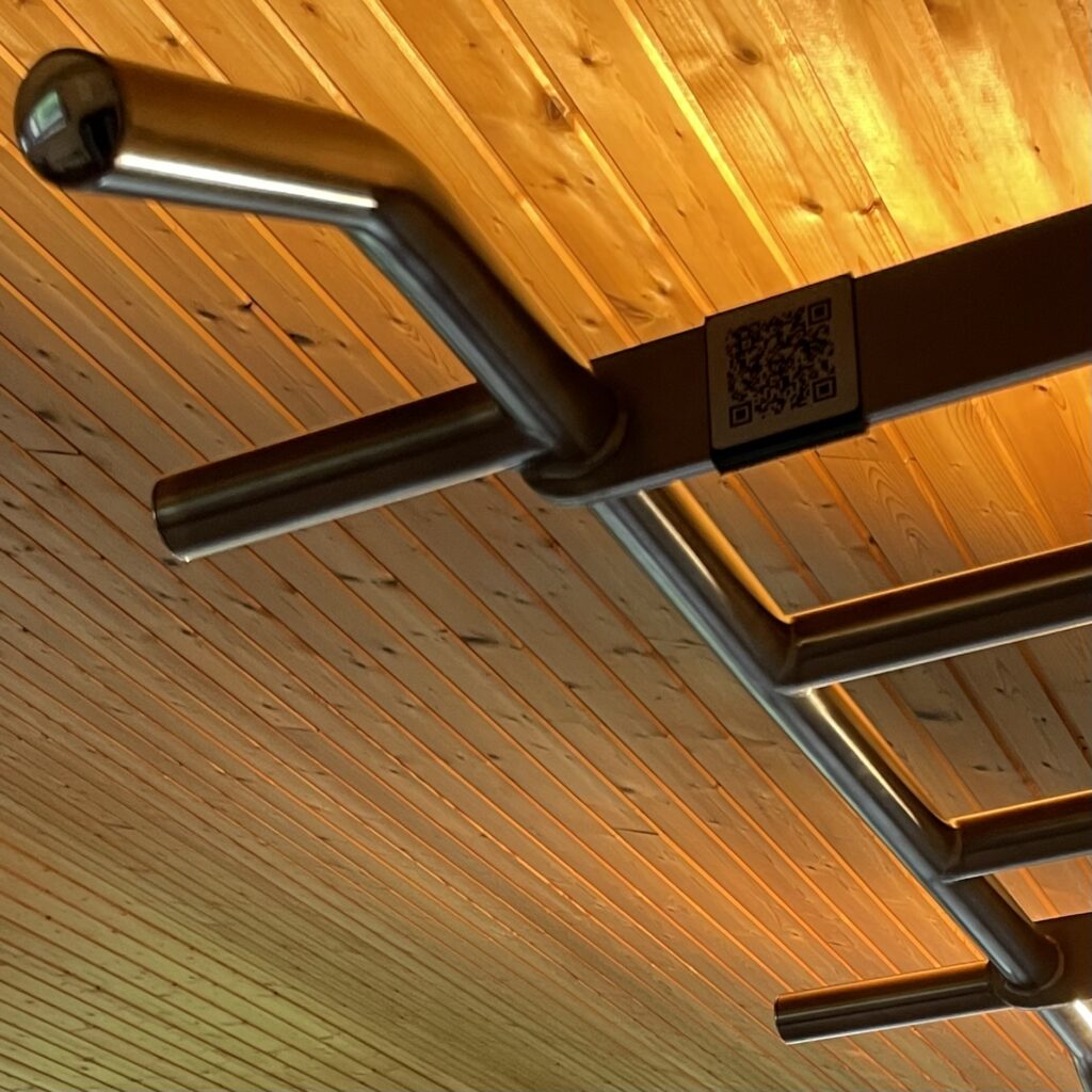 Klimmstange Stahl von unten mit Holztäferdecke und warmer Beleuchtung im Gym Studio von Jo Angele in Wigoltingen. 