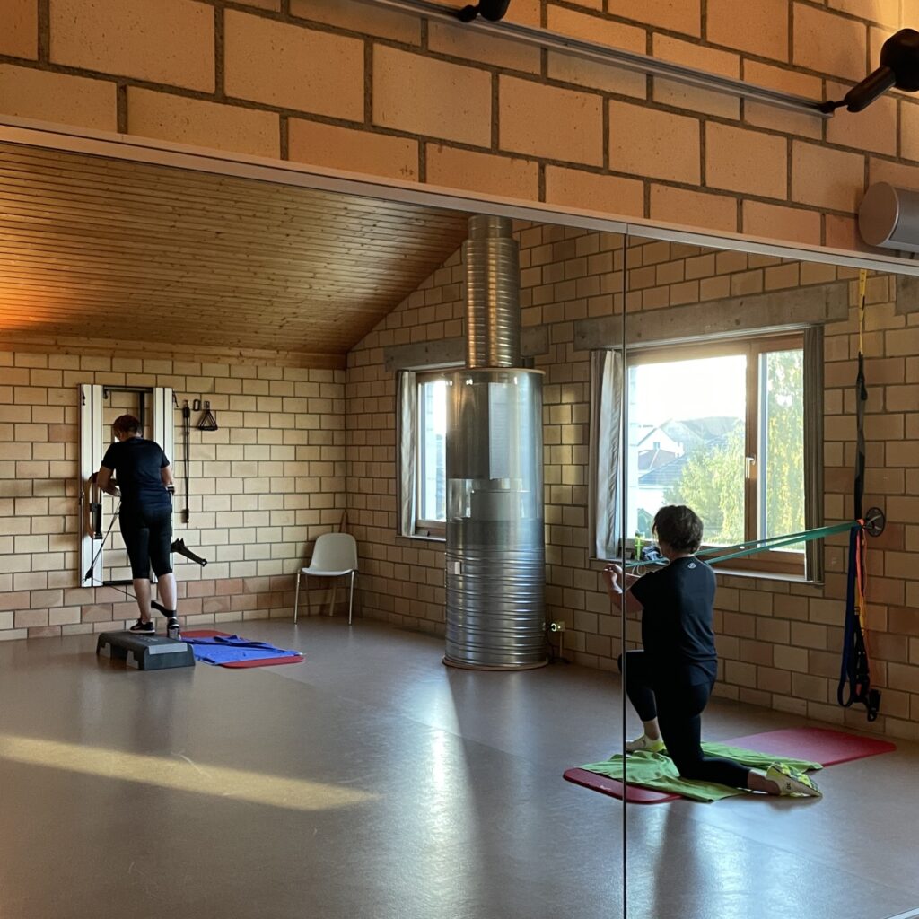 Zwei Kundinnen trainineren am Eisenhorn Kick-Backs am Kabelzug und Paloff Press mit Widerstandsband im Gruppenkurs im Atrium Gym Studio in Wigoltingen.