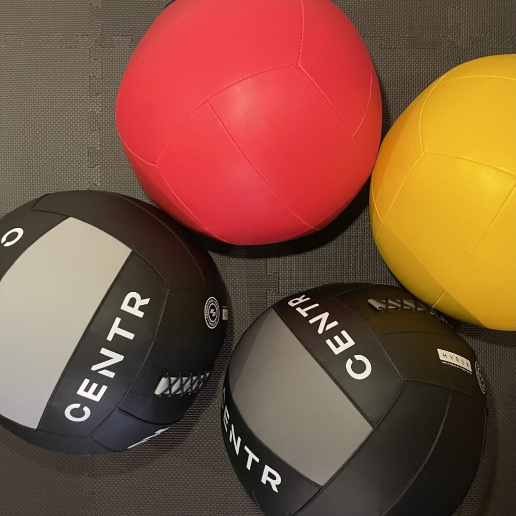 Medizinbälle rot, gelb und schwarz für Wall Balls Übung wie im HYROX.